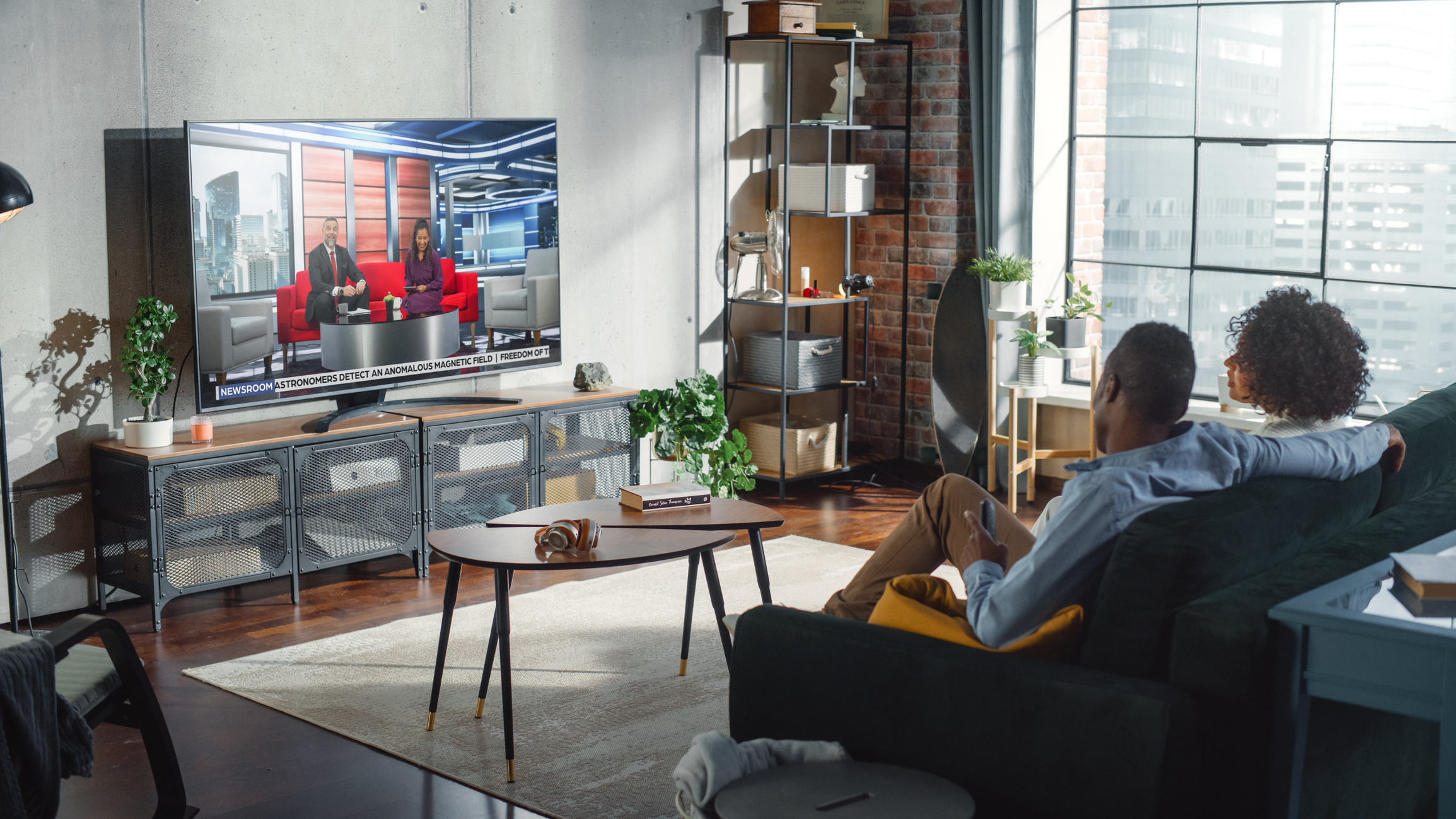 Couple sitting on couch at home watching TV representing a geotargeted CTV advertisement.
