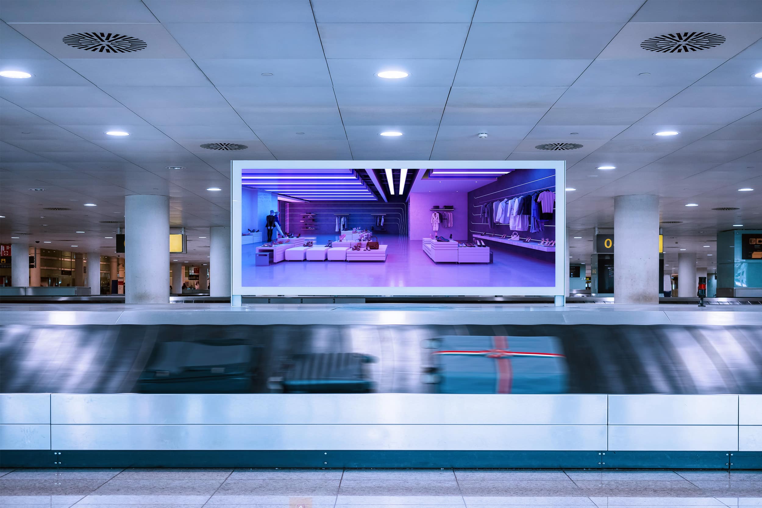 Digital out of home advertising screen positioned above an airport baggage claim.
