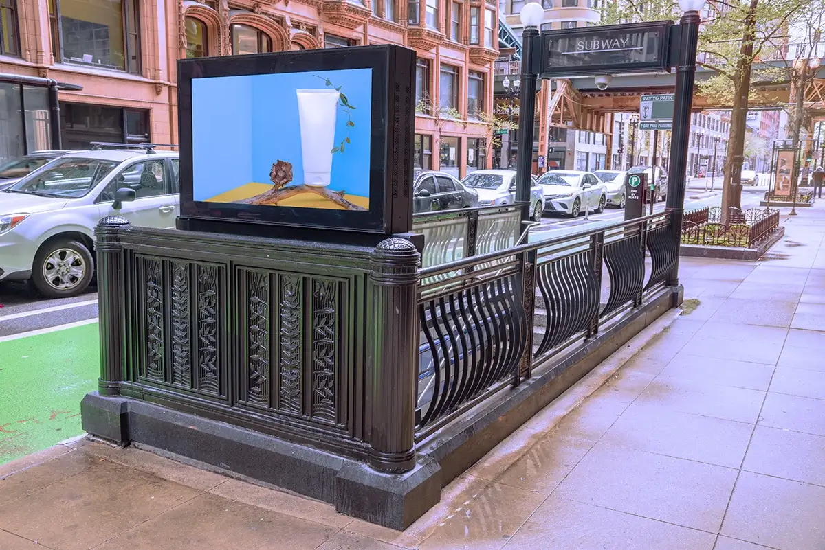 Digital out of home advertising screen placed at a subway entrance along a busy urban street.